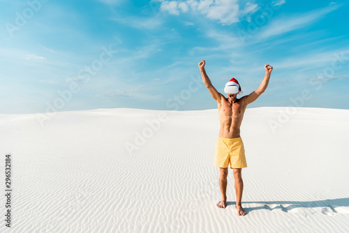 sexy man in santa hat with virtual reality headset showing yes gesture on beach in Maldives