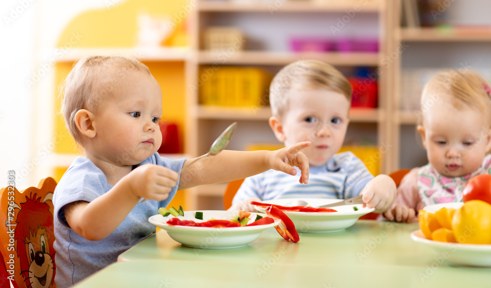 Time to eat in kindergarten or creche. Nursery babies eating healthy food in day care centre Time to eat in kindergarten or creche. Nursery babies eating healthy food in day care centre