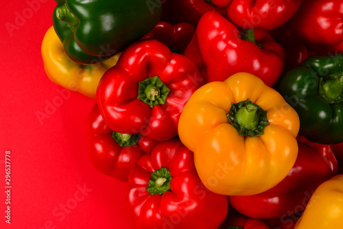 Fresh red, yelow, green bell pepper on a red background.