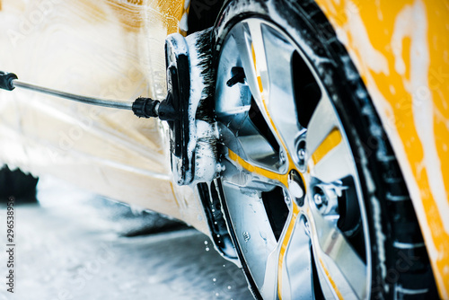 Fotografie Man washing a car using brush and soap or foam