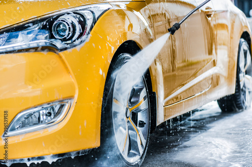 Car wash using high pressure water. Detail of manual wheel cleaning concept. photo