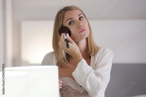 girl near the mirror does makeup for herself. 