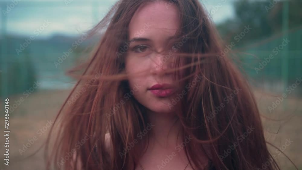 Portrait of a beautiful girl in a red blouse who is looking at the camera. Hair fluttering in the wind. Passionate look of the brown eyes of a girl. Portrait of a beautiful girl in a red blouse who is looking at the camera. Hair fluttering in the wind. Passionate look of the brown eyes of a girl.