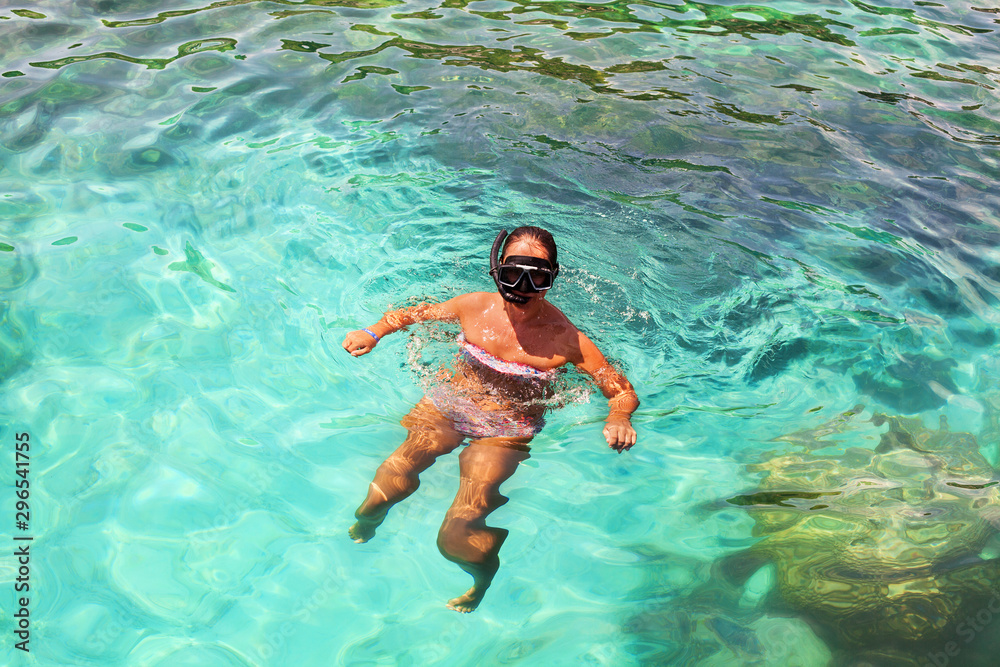 Young girl with diving mask and snorkel dives in clear blue sea water, adult woman in white bikini swims in turquoise clean transparent ocean water, tropical coral reef snorkeling on summer holidays