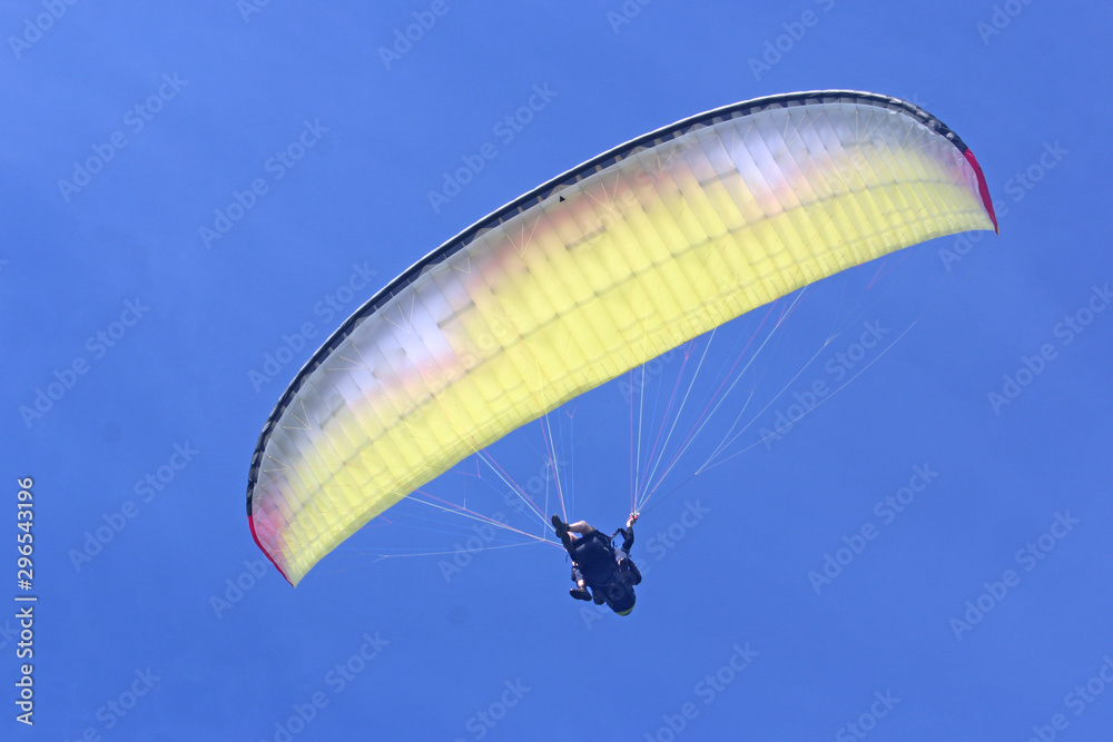 Tandem Paraglider flying wing in a blue sky Tandem Paraglider flying wing in a blue sky