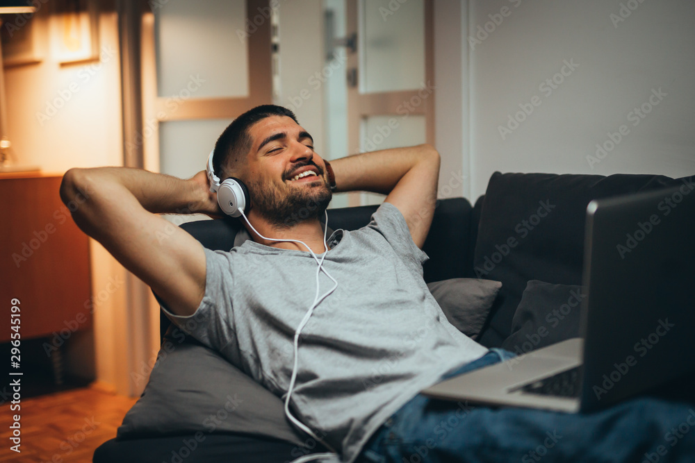 Obraz premium man relaxing in sofa at his apartment listening to music