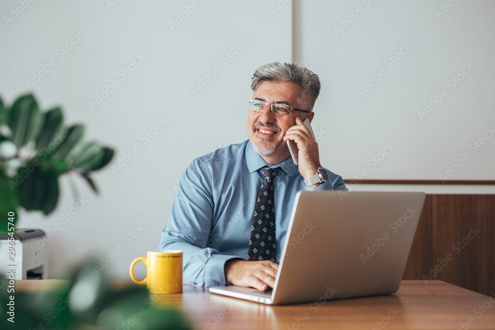 senior manager using mobile phone sitting desk in his office senior manager using mobile phone sitting desk in his office