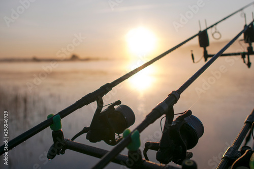 fisherman with fishing rods at sunrise on the lake