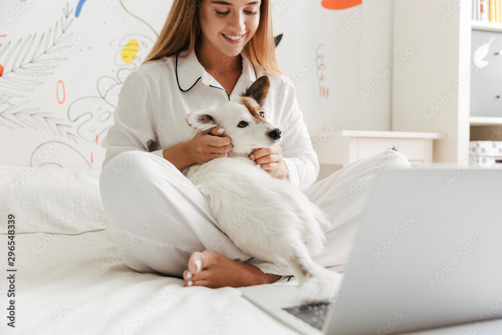 Cute girl in pajama at home on bed with her dog Cute girl in pajama at home on bed with her dog