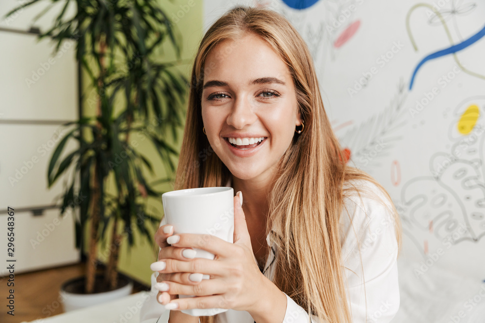 Cute girl in pajama at home on bed drinking coffee. Cute girl in pajama at home on bed drinking coffee.
