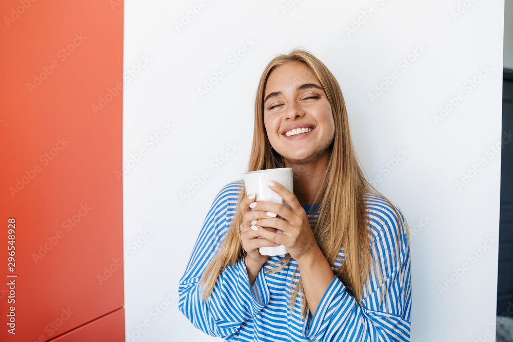 Cute girl at home near wall drinking tea holding glass. Cute girl at home near wall drinking tea holding glass.