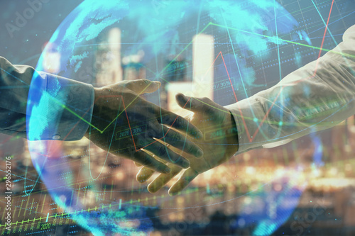 Double exposure of financial chart and world map on cityscape background with two businessmen handshake. Concept of international investment