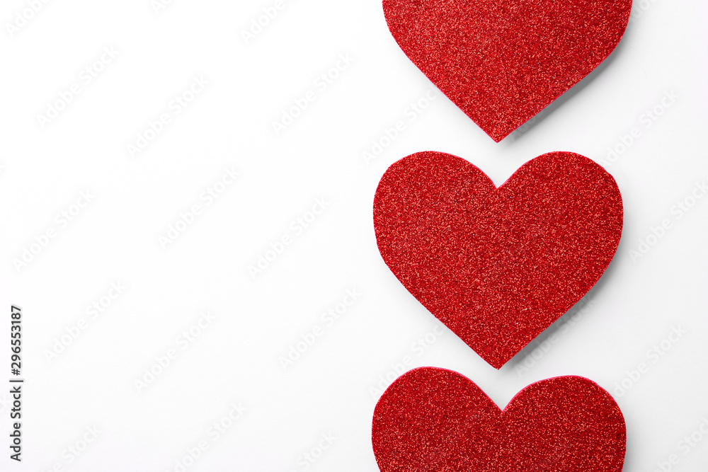 Red shiny paper hearts on white background, top view