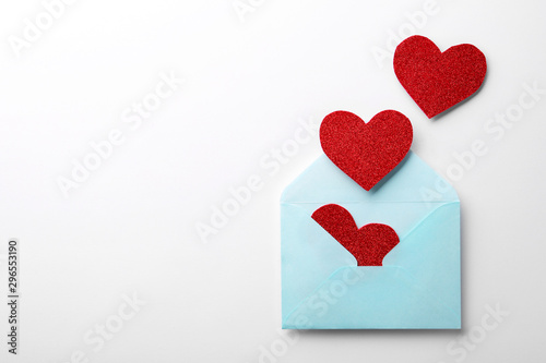 Red shiny paper hearts and envelope on white background, top view © New Africa