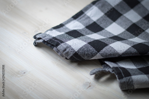 Checked black and white kitchen towel on wooden surface. Selective focus 