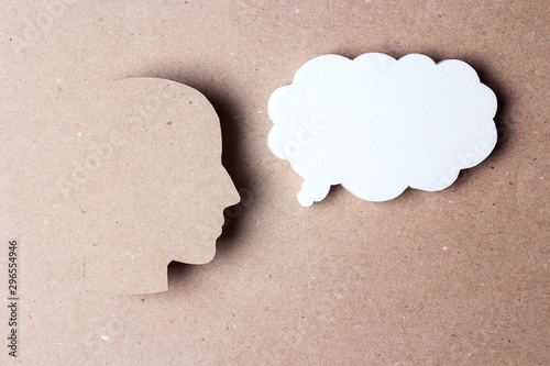 Head silhouette with speech bubble on brown paper background. photo