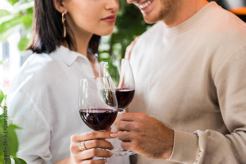 cropped view of happy man holding glass with red wine near girl cropped view of happy man holding glass with red wine near girl