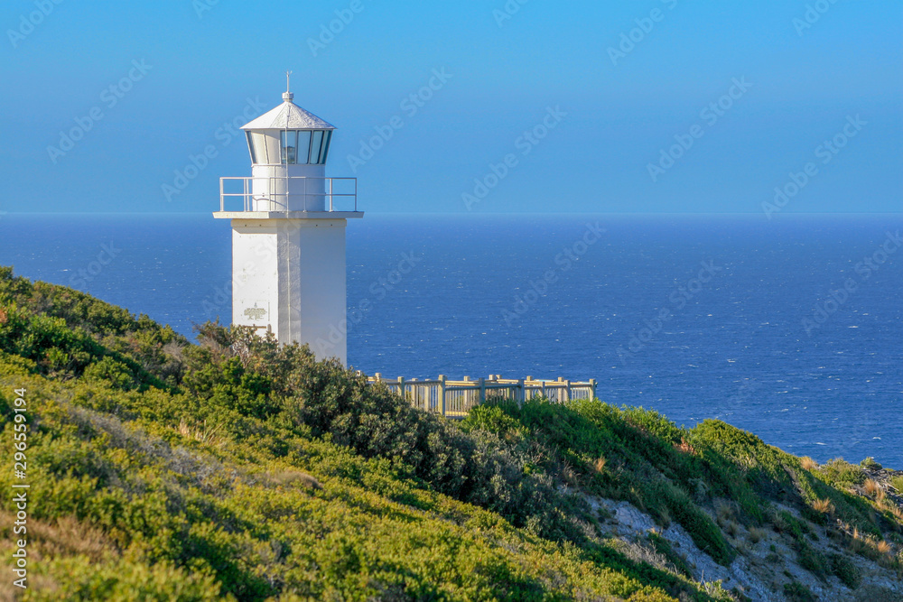 White lighthouse against blue sky and ocean