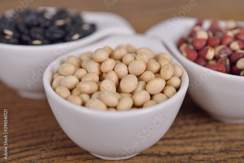 navy beans, cowpeas and black beans in ceramic cup on wooden background