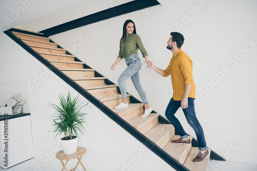 I will show you our bedroom. Full length profile photo of handsome guy and his pretty lady going up stairs in new modern flat indoors wear casual clothes