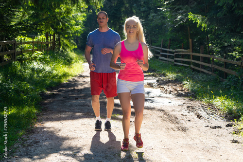 Fototapeta Naklejka Na Ścianę i Meble -  Running fitness couple of runners doing sport on road outdoor. Active living man and woman jogging training cardio in summer outdoors nature.