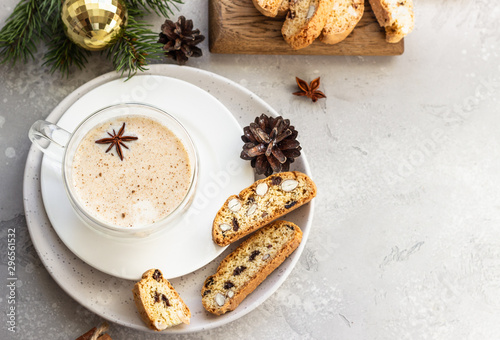 Eggnog. Christmas milk cocktail with cinnamon and anise, served in glass mug with biscotti, winter spices, fir branches and cones.