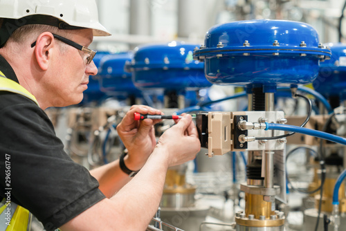 engineer checks an pneumatic valve with a screwdriver photo