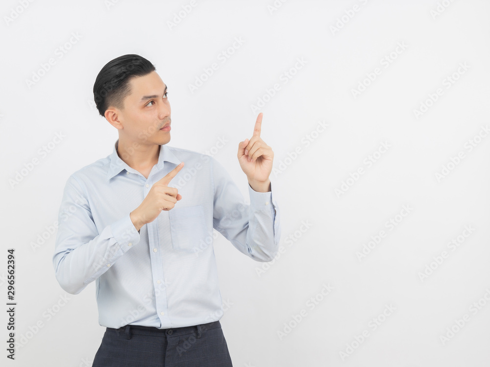 Young asian business man with blue shirt pointing to the side with a finger to present a product or an idea while looking forward surprising isolated on white background. Young asian business man with blue shirt pointing to the side with a finger to present a product or an idea while looking forward surprising isolated on white background.
