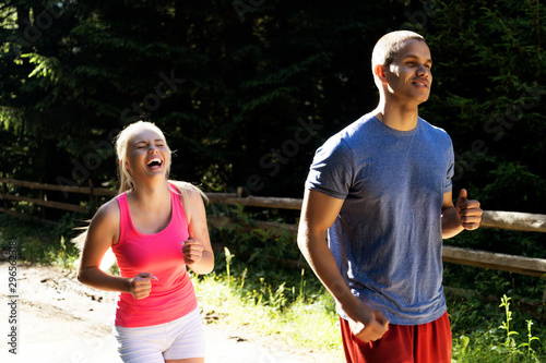 Running fitness couple of runners doing sport on road outdoor. Active living man and woman jogging training cardio in summer outdoors nature.