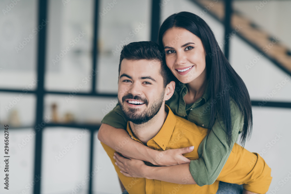 Closeup photo of just married husband guy and his wife lady holding piggyback carry bride to new bought flat showing unexpected wedding surprise wear casual clothes