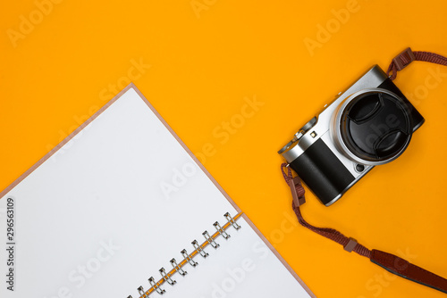 Travel concept with camera and note on orange background