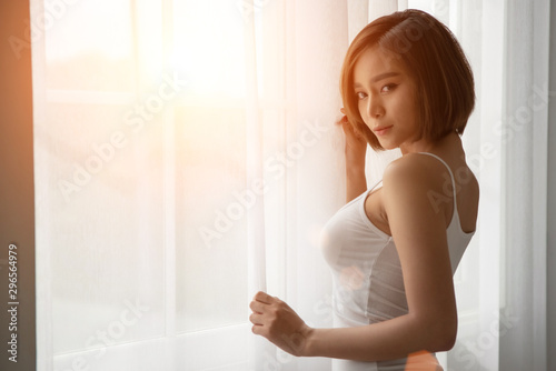 Young Woman Standing By Window At Home