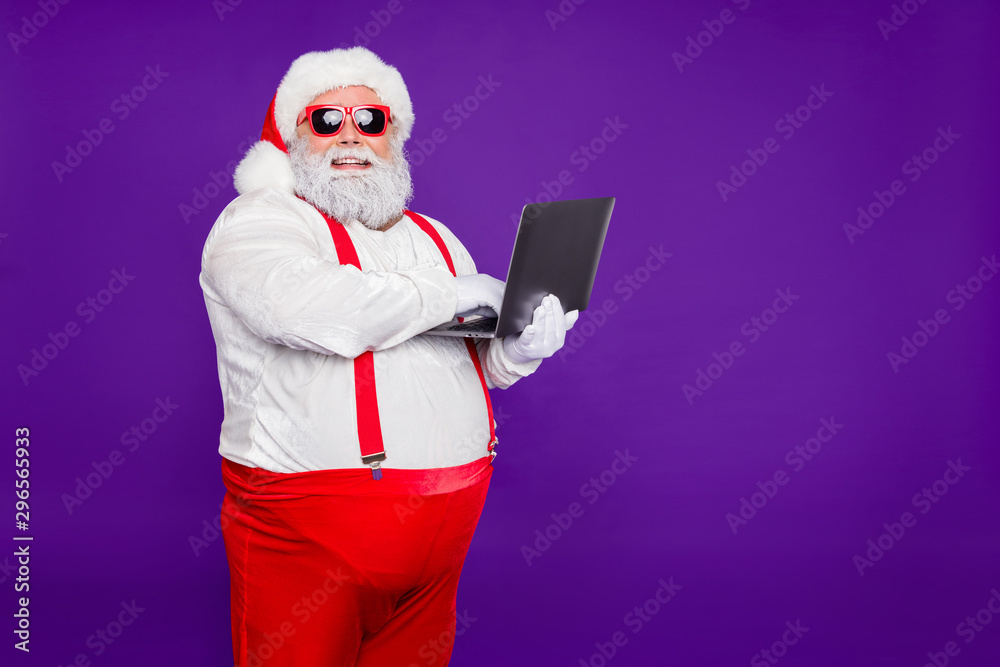 Profile side view portrait of his he nice confident cheerful cheery fat thick bearded Santa holding in hands laptop typing e-mail letter isolated on bright vivid shine vibrant violet lilac background - obrazy, fototapety, plakaty 