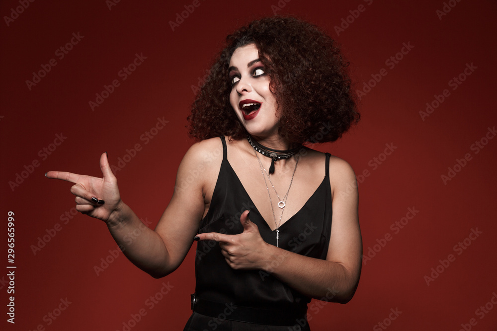 Image of witch girl in black dress with halloween makeup pointing finger Image of witch girl in black dress with halloween makeup pointing finger