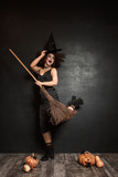 Full length image of witch girl in halloween costume flying on broom