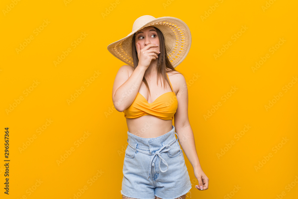Young caucasian woman wearing a straw hat, summer look thoughtful looking to a copy space covering mouth with hand. Young caucasian woman wearing a straw hat, summer look thoughtful looking to a copy space covering mouth with hand.