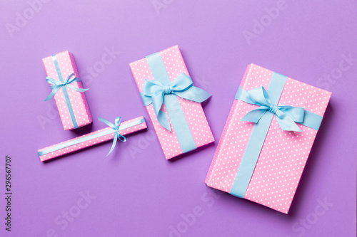 Gift box with blue bow for Christmas or New Year day on purple background, top view