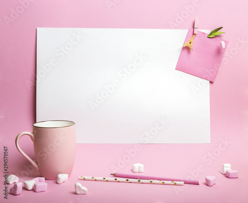 Cup on pink background with sheet of white paper, heart marshmallows and pensils photo