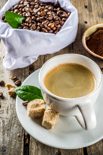 Cup of espresso with coffee beans. ground coffee and leaves on rustic background