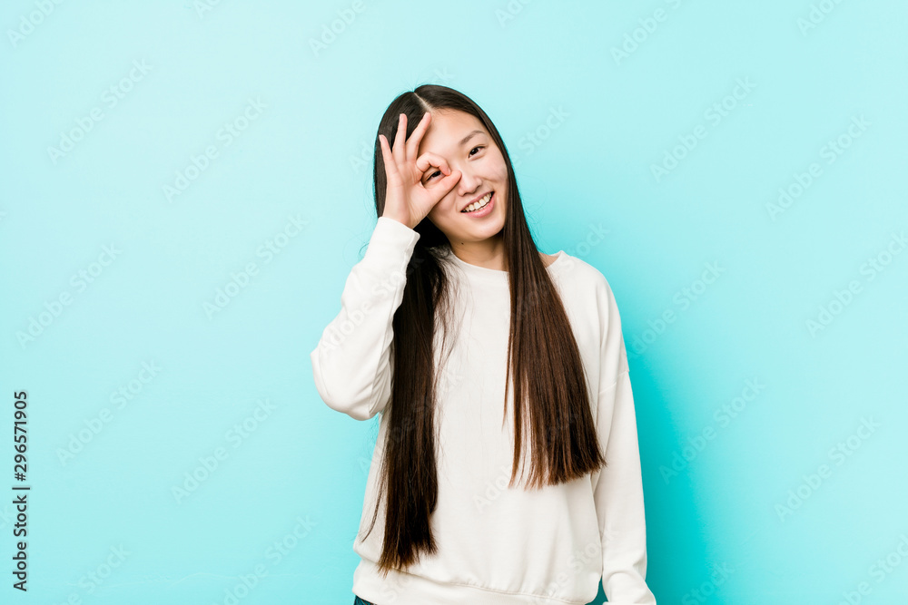 Young pretty chinese woman excited keeping ok gesture on eye. Young pretty chinese woman excited keeping ok gesture on eye.