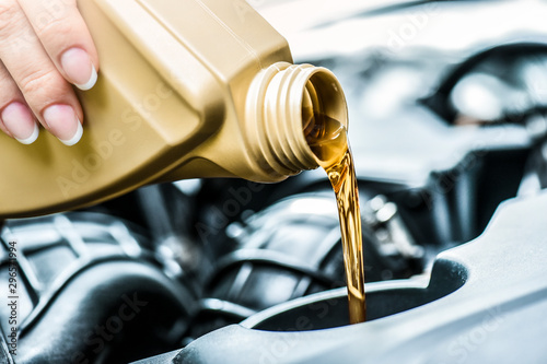 Woman hand pour motor oil to car engine. Vehicle maintenance and top up fluids and change liquids.