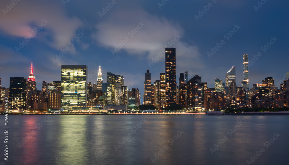 Fototapeta vista del skyline de Manhattan , Nueva York,USA,por la noche, desde la zona de Dumbo. Fotografia de larga exposicion, con reflejos en el agua con textura seda