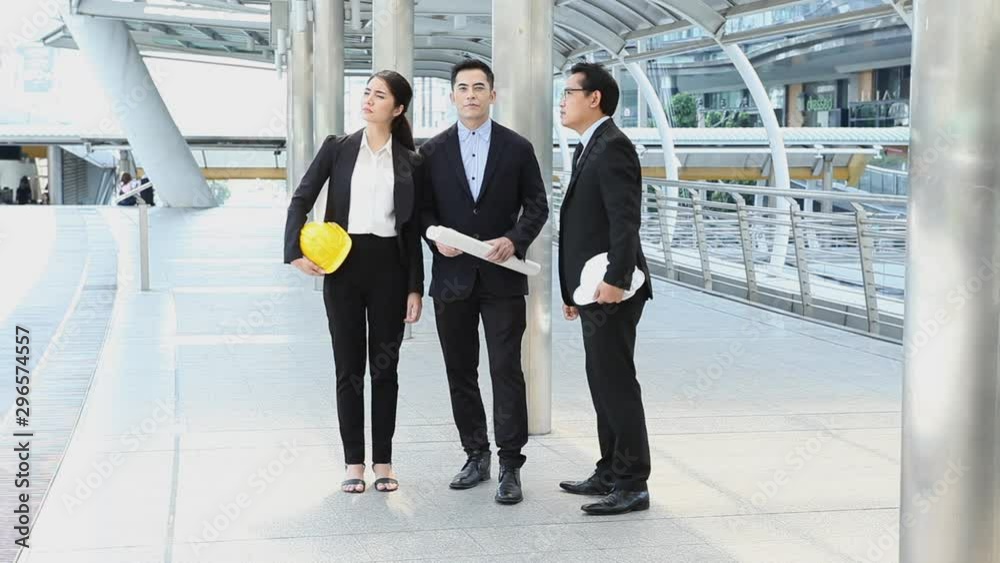 business man holding the blueprint discussion with architects and Construction engineers at construction site or building site at city outdoors   group of businesspeople discussing outside . teamwork.