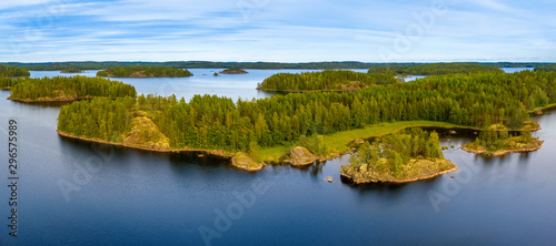 Fototapeta Naklejka Na Ścianę i Meble -  Aerial view of of small islands on a blue lake Saimaa. Landscape with drone. Blue lakes, islands and green forests from above on a cloudy summer morning. Lake landscape in Finland.