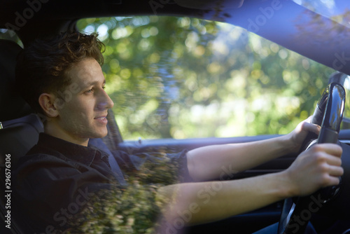 Sideview of a smiling young man driving with beautiful reflections