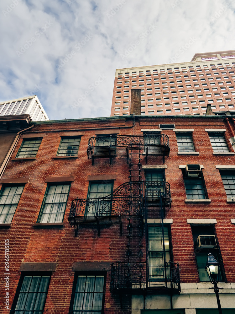 Obraz premium arquitectura antigua con escaleras exteriores antiincendios,junto a rascacielos modernos, en el distrito historico de Manhattan, Nueva York, USA