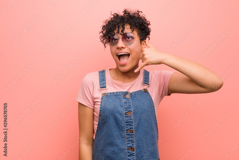 Young mixed african american teenager woman showing a mobile phone call gesture with fingers. Young mixed african american teenager woman showing a mobile phone call gesture with fingers.
