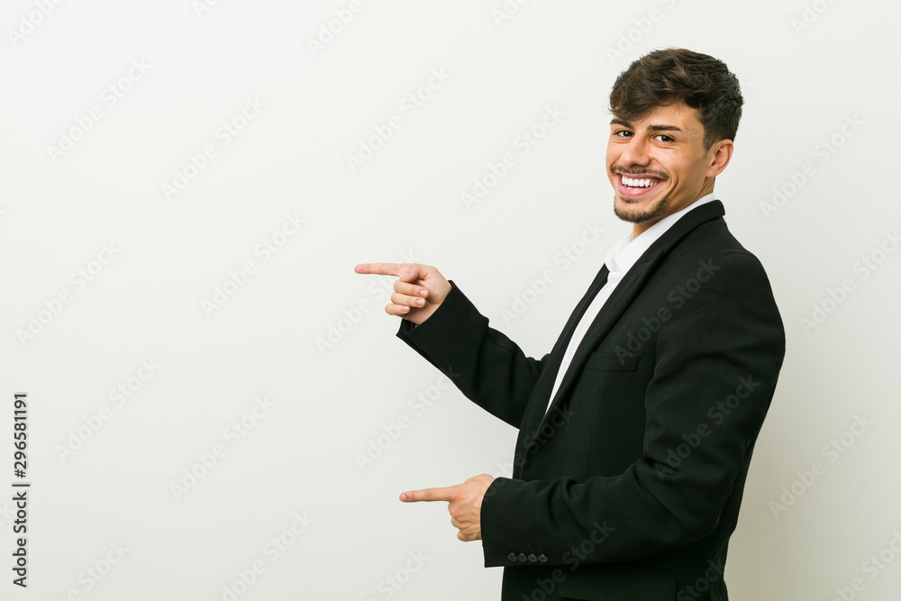 Young business hispanic man excited pointing with forefingers away. Young business hispanic man excited pointing with forefingers away.