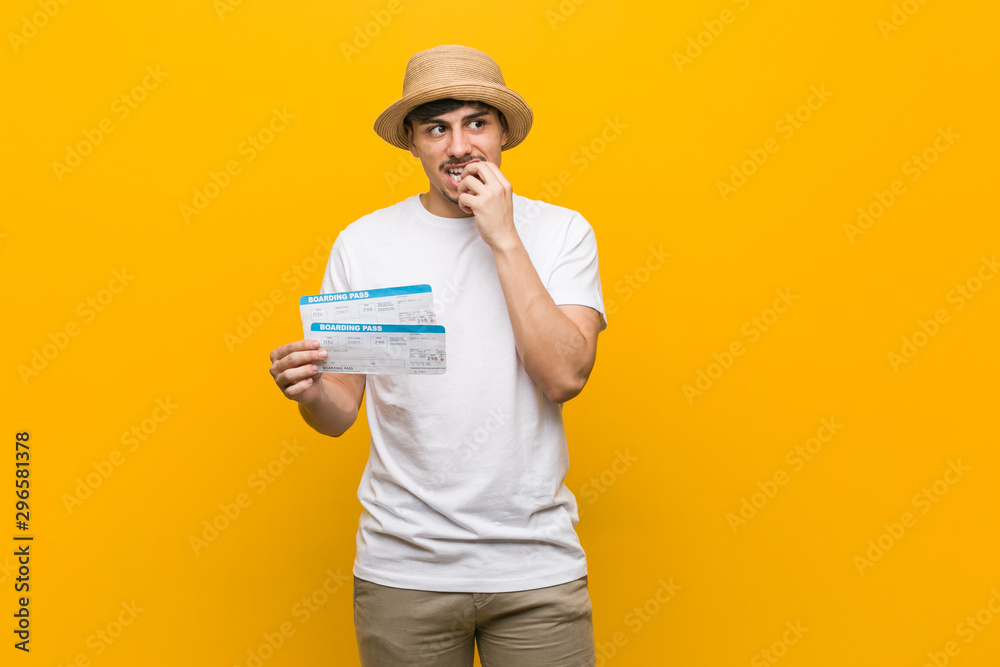 Young hispanic man holding an air tickets relaxed thinking about something looking at a copy space. Young hispanic man holding an air tickets relaxed thinking about something looking at a copy space.
