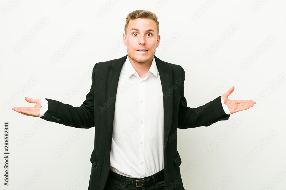 Young caucasian business man confused and doubtful shrugging shoulders to hold a copy space.